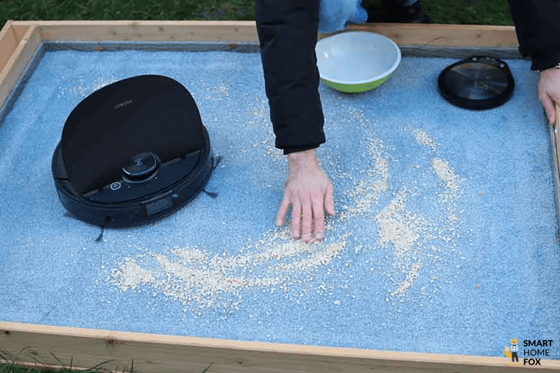 Im Saugroboter Testareal werden Haferflocken auf dem Teppich verstreut